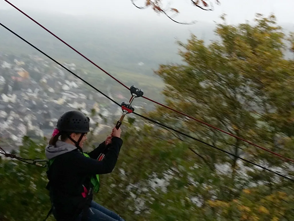 Person hängt in der Seilrutsche über dem Weinberg.